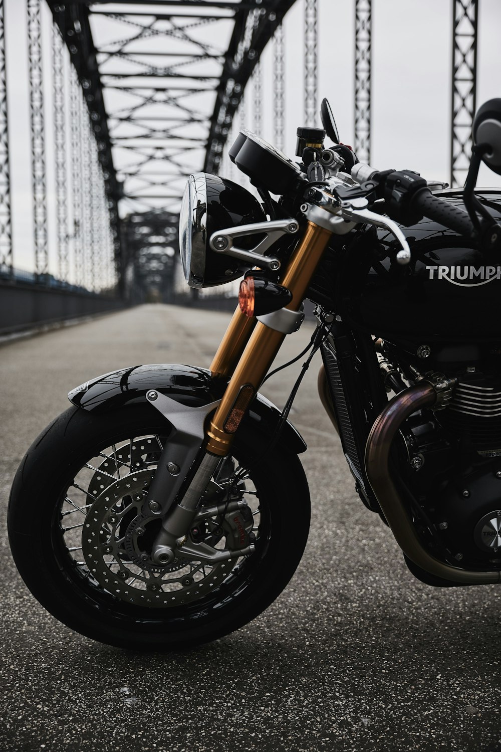 a black motorcycle parked on the side of a bridge