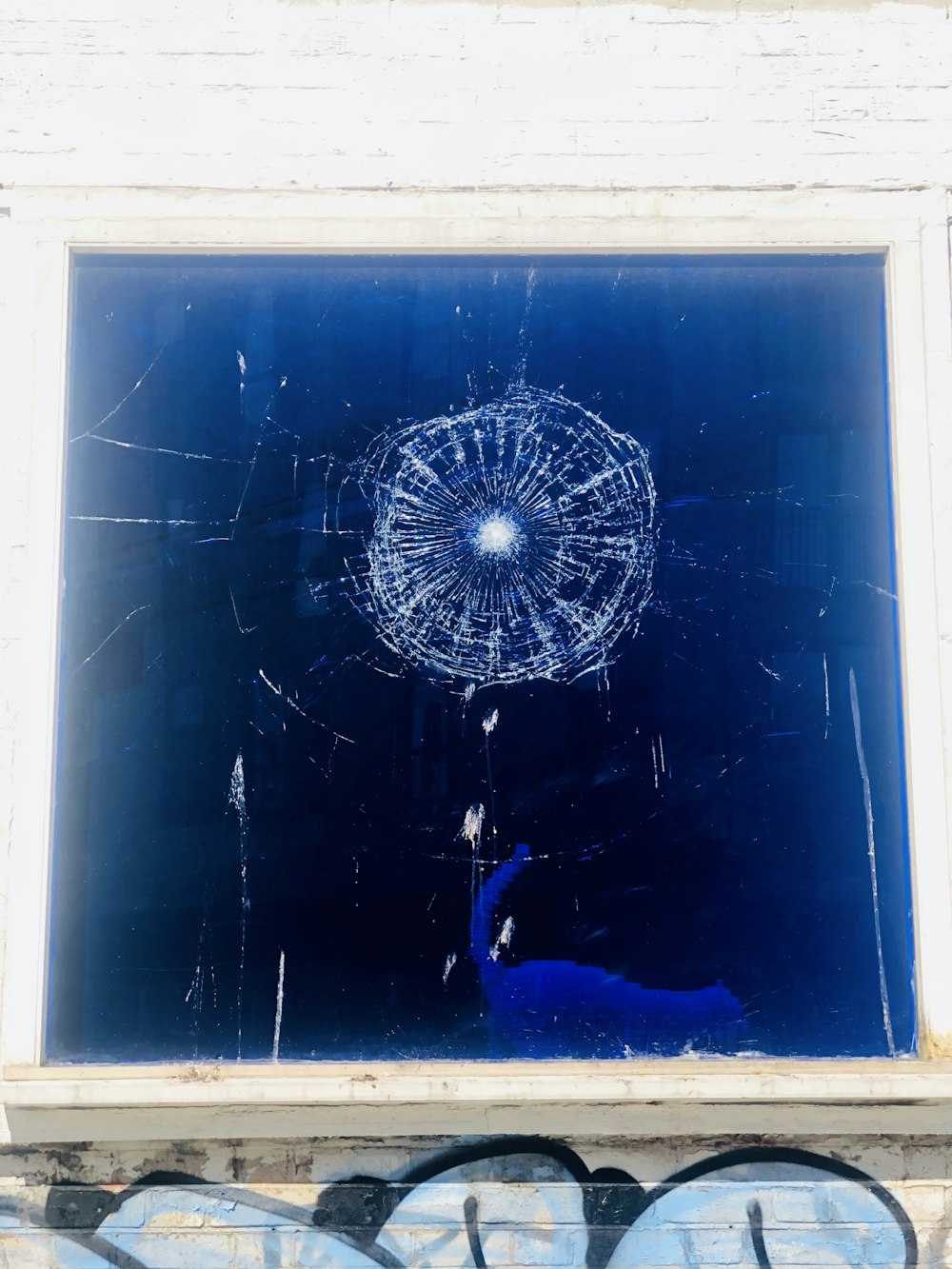 a broken window with graffiti on it