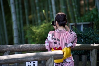 woman in white and purple floral shirt sitting on brown wooden bench during daytime