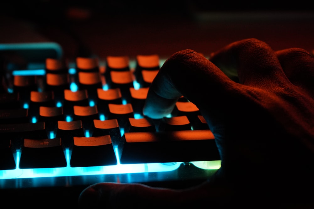 La mano de las personas en el teclado de la computadora con luz azul