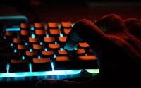 persons hand on blue lighted computer keyboard