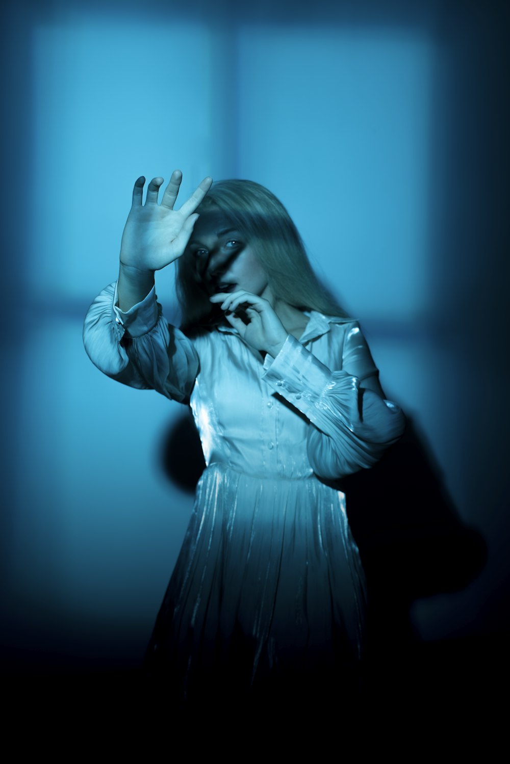 woman in white dress shirt covering her face with her hands