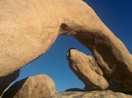 The iconic Pravčická brána sandstone arch towering against a clear blue sky.
