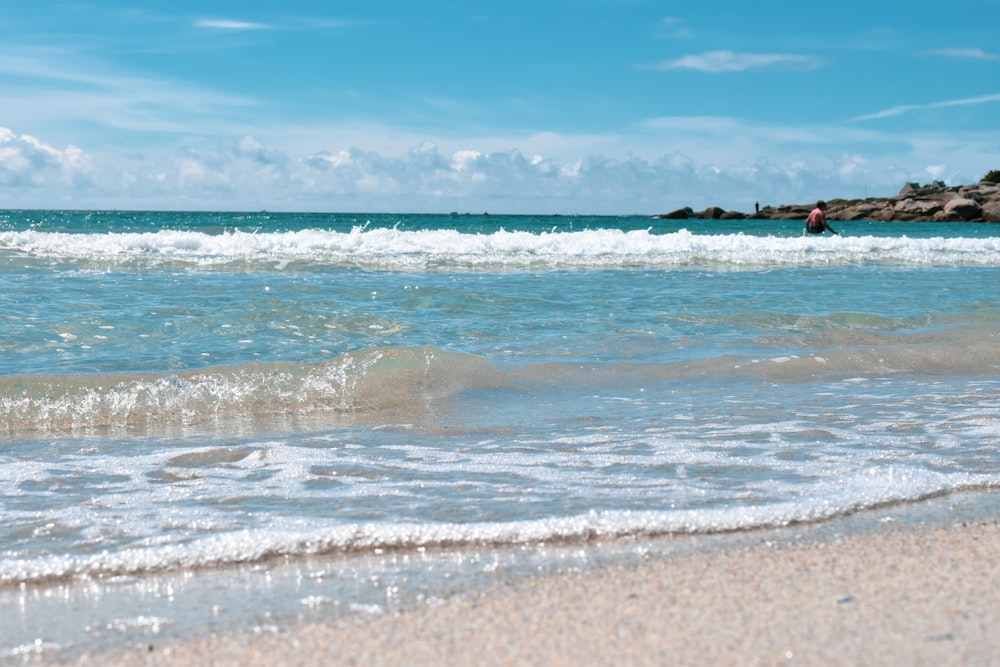 people surfing on sea waves under blue sky during daytime