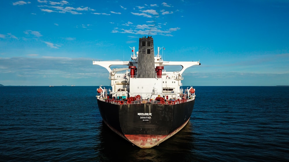 rotes und schwarzes Schiff auf See unter blauem Himmel tagsüber