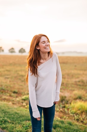 woman in white long sleeve shirt and blue denim jeans standing on green grass field during