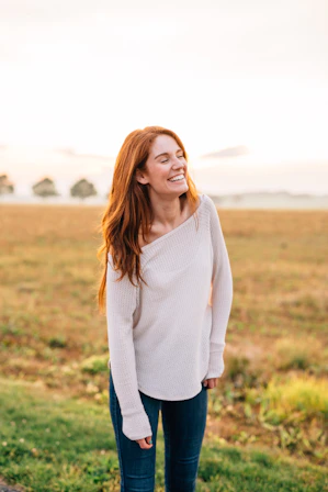 woman in white long sleeve shirt and blue denim jeans standing on green grass field during