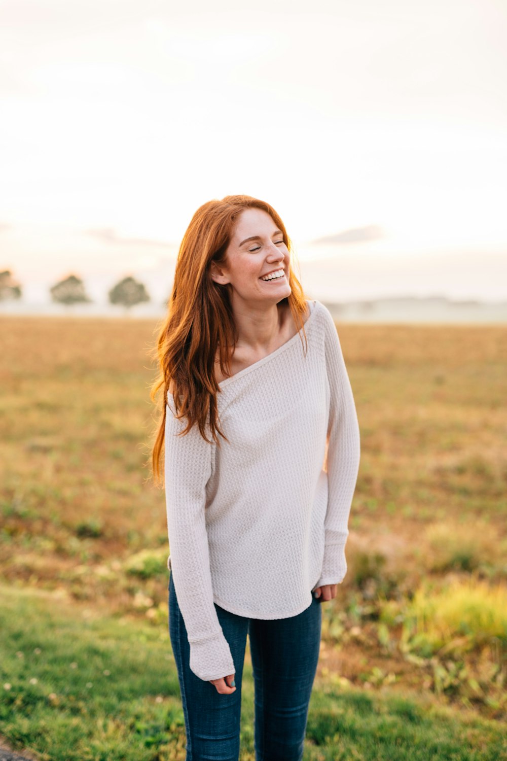 woman in white long sleeve shirt and blue denim jeans standing on green grass field during