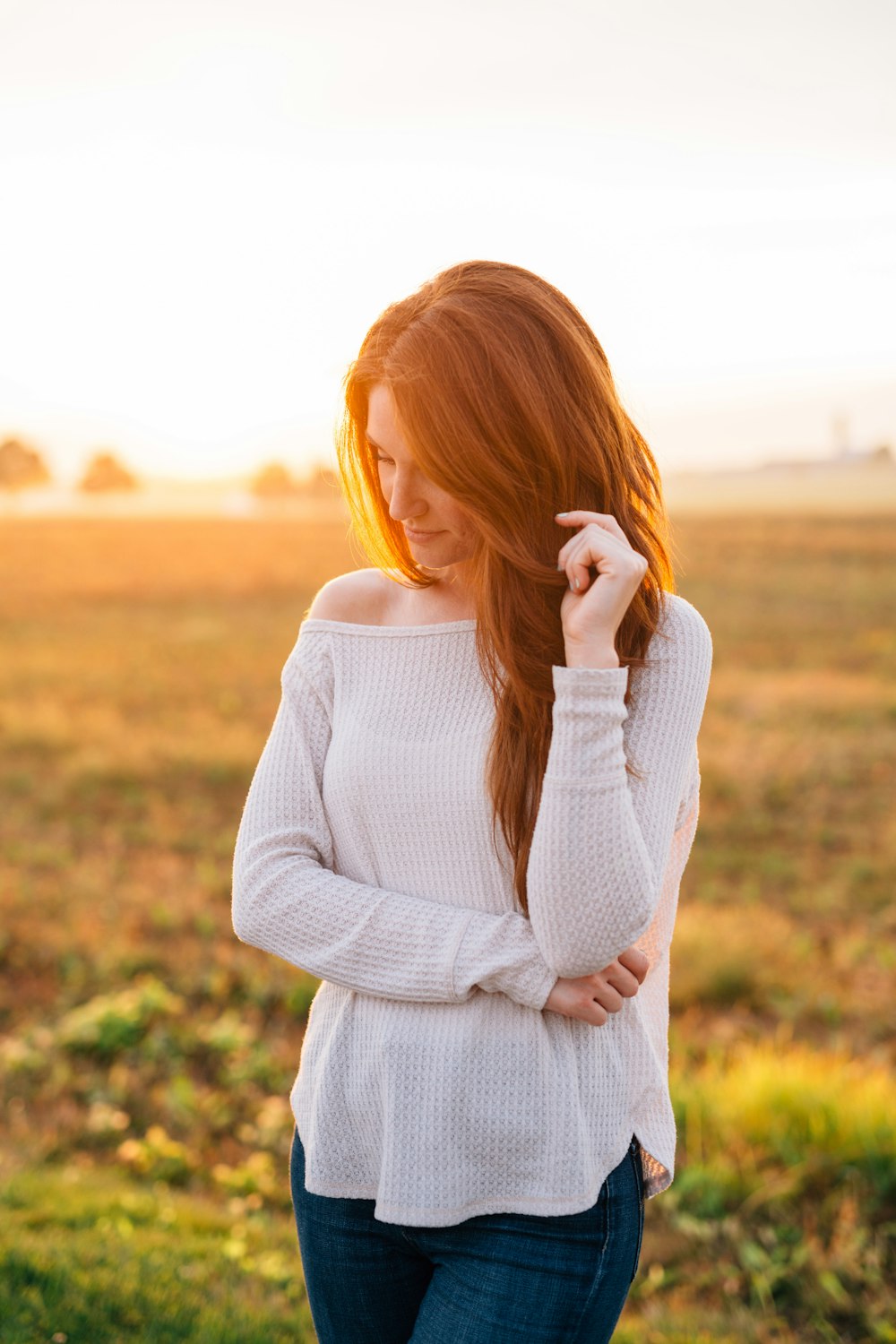 Mujer en suéter blanco de pie en el campo de hierba verde durante el día
