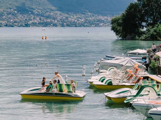 woman in white shirt sitting on yellow and green kayak on sea during daytime in Lac d'Annecy France