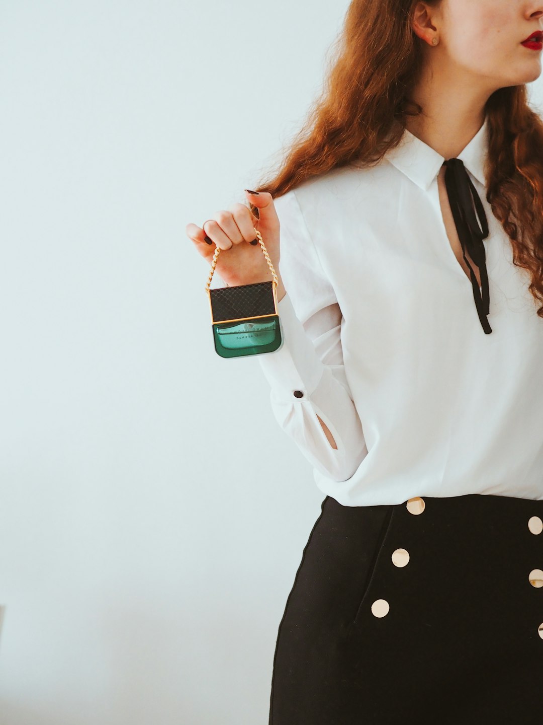 woman in white dress shirt and black skirt holding green and white plastic bottle