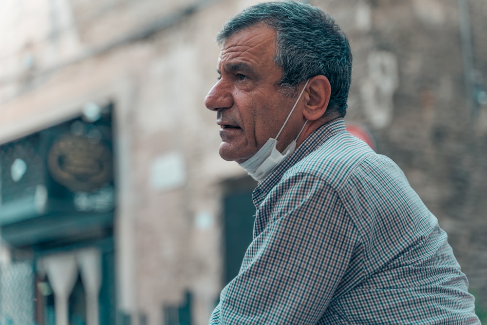 man in blue and white checkered dress shirt wearing white earbuds