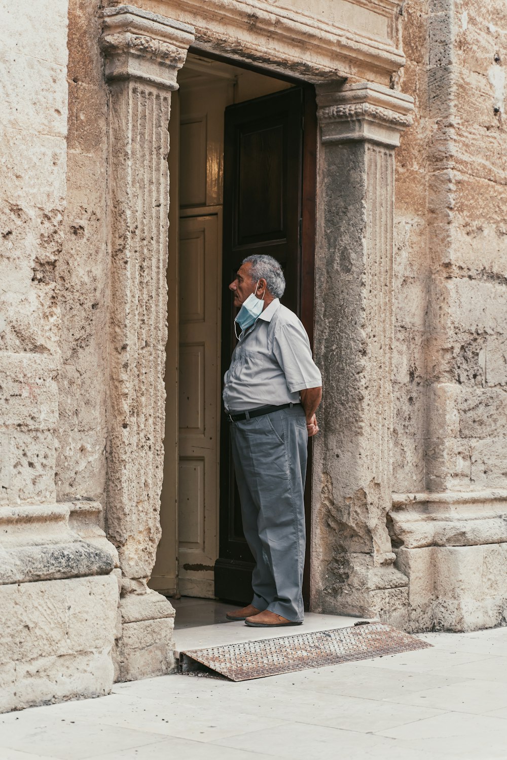 man in white thobe standing beside brown concrete wall during daytime