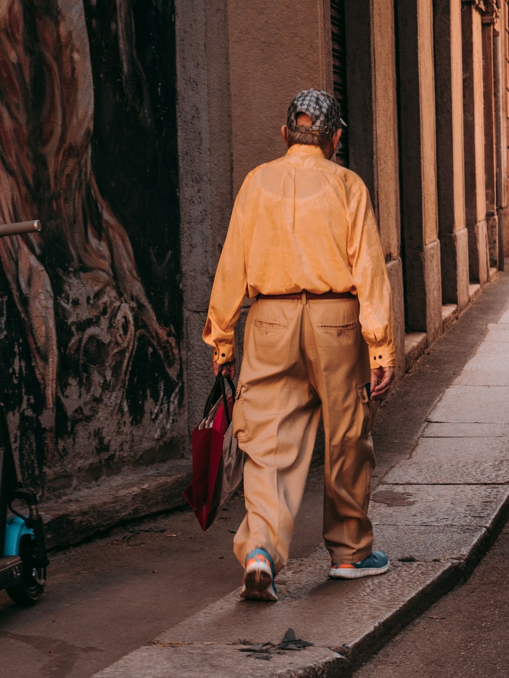 man in yellow thobe standing on sidewalk during daytime