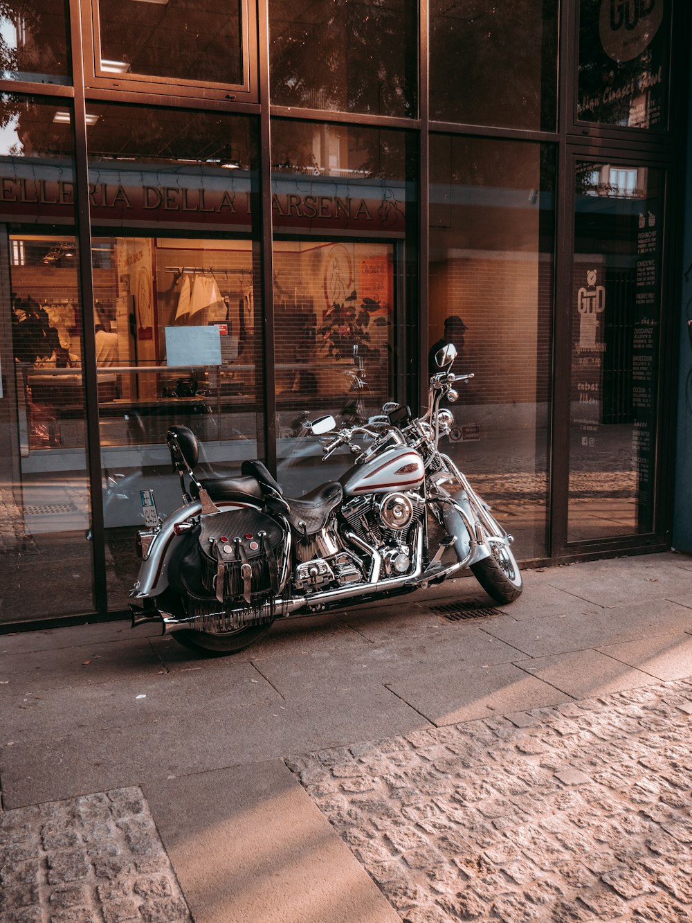 Motocicleta cruiser negra y plateada estacionada al lado de la tienda