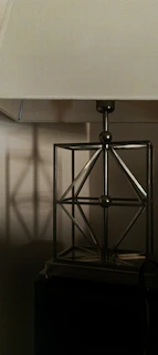 A minimalist table lamp with a geometric base illuminating a clean, modern workspace
