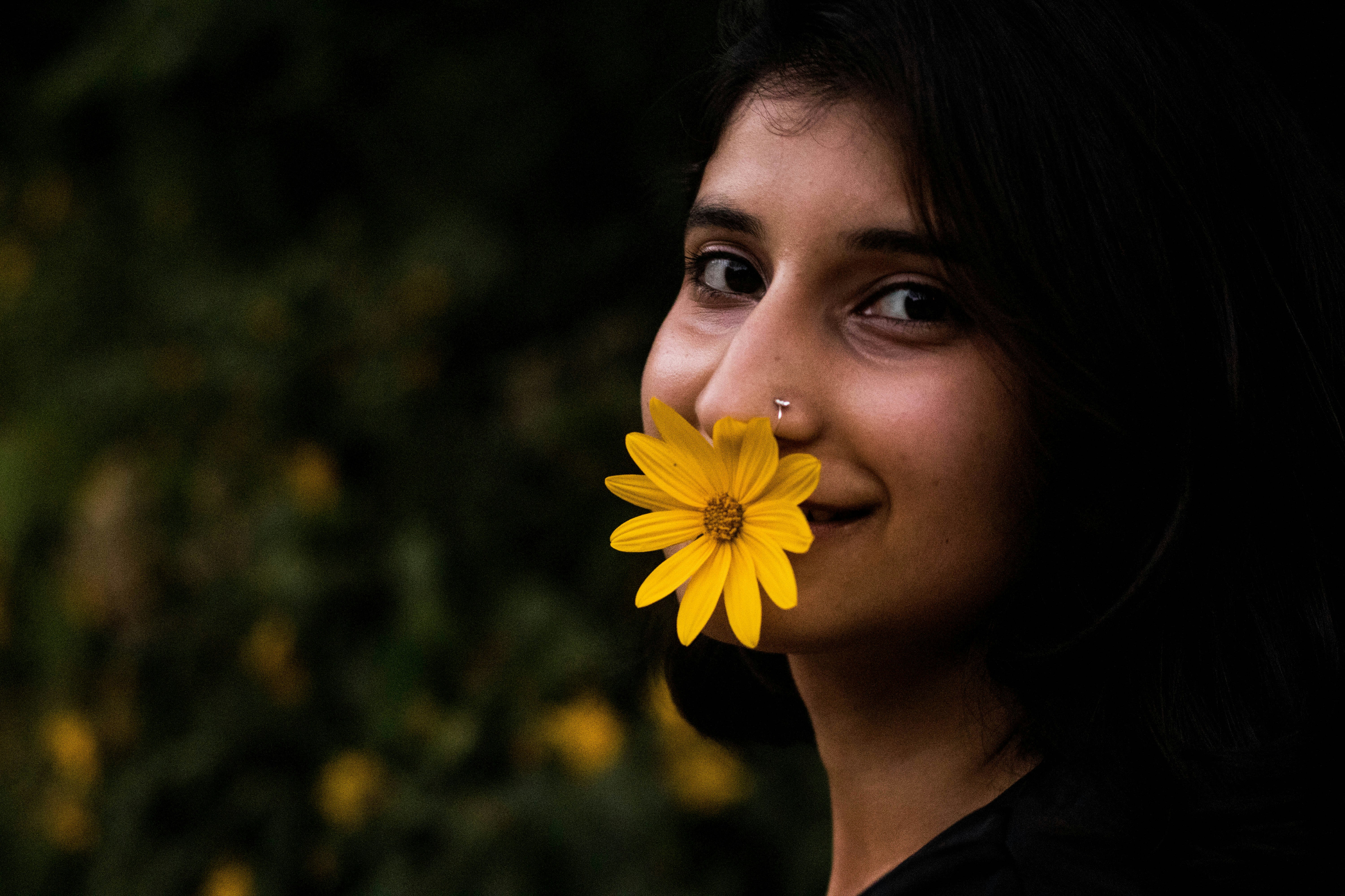 woman in black shirt holding yellow flower