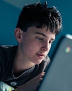 man in black shirt looking at blue laptop computer