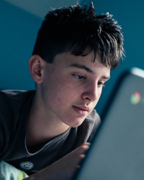 man in black shirt looking at blue laptop computer