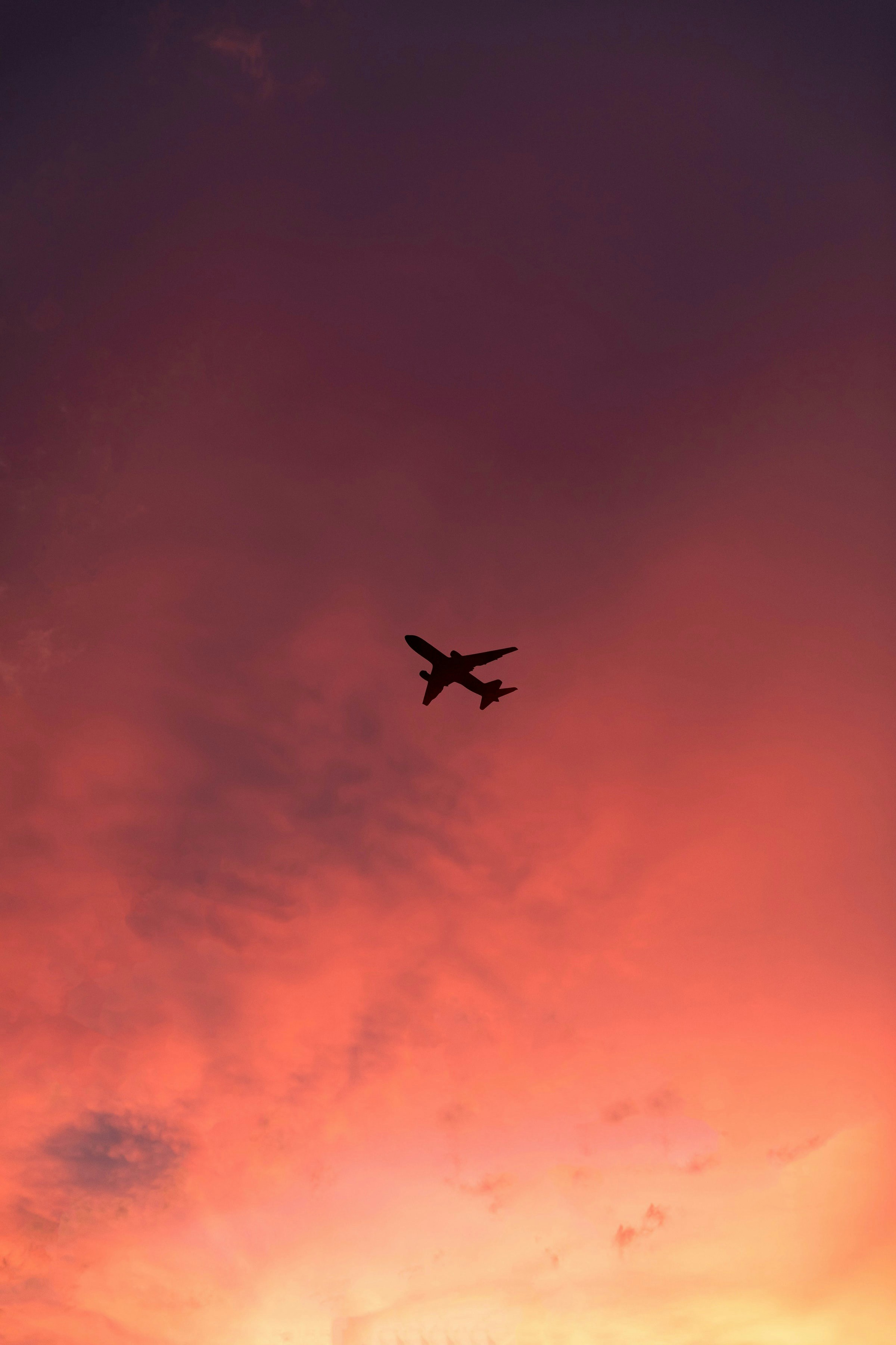 Aereo in volo al tramonto con cielo arancione e rosa, atmosfera epica da viaggio