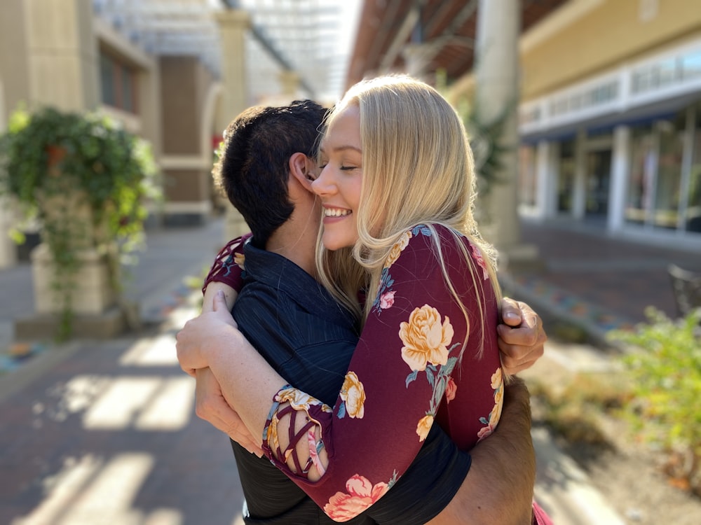 woman in black and red floral shirt carrying girl in black shirt