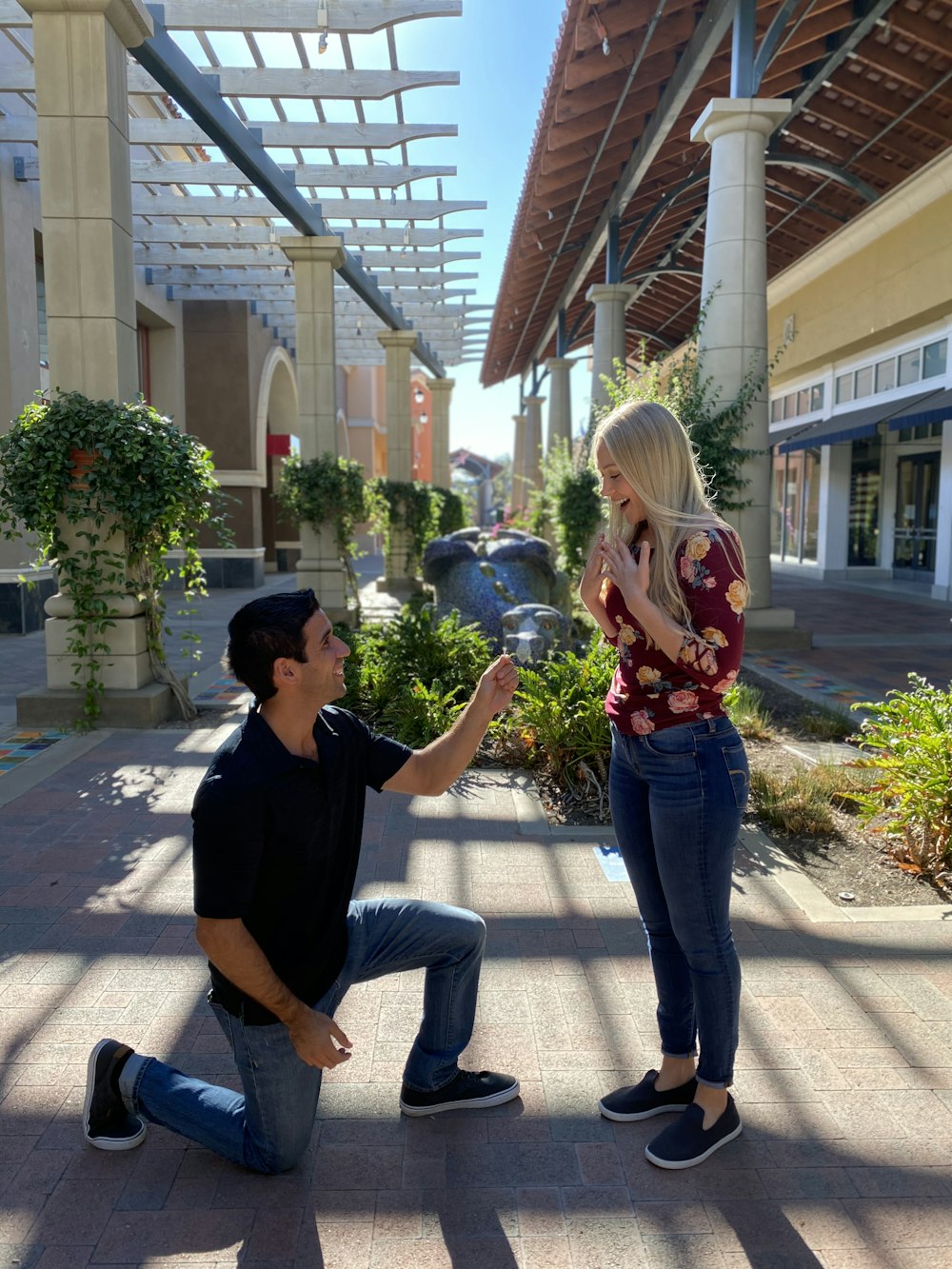 man in black crew neck t-shirt and blue denim jeans holding woman in red and