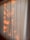 Vertical blinds partially illuminated by warm sunlight, casting soft, natural patterns and shadows across the surface.