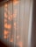 Vertical blinds partially illuminated by warm sunlight, casting soft, natural patterns and shadows across the surface.