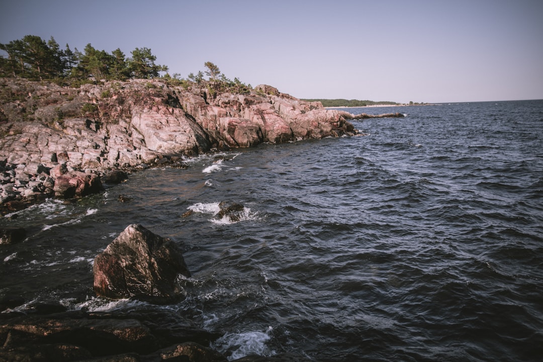 brown rocky mountain beside body of water during daytime