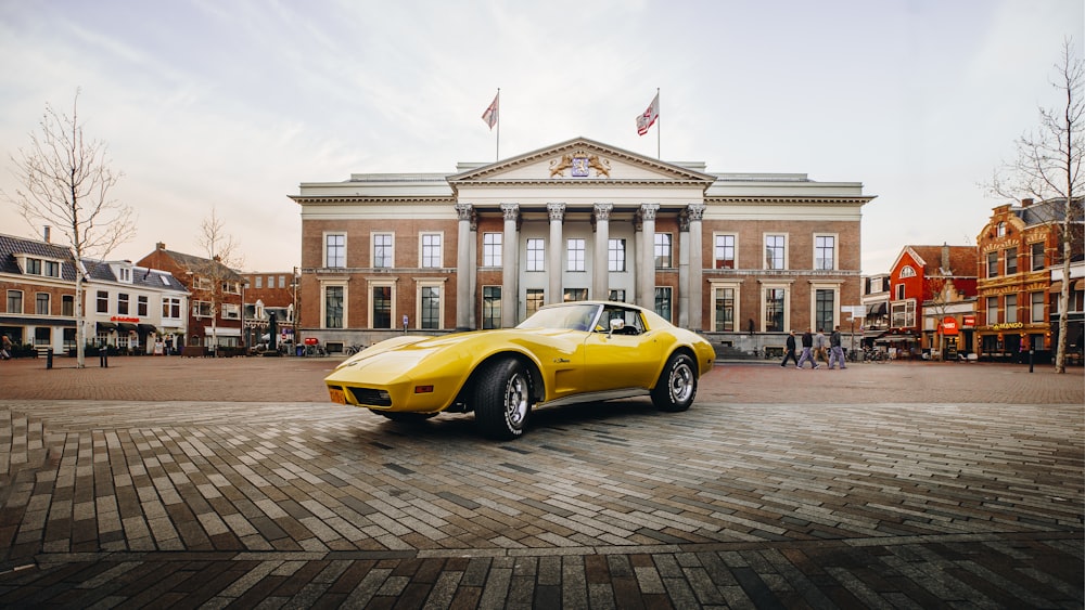 yellow porsche 911 parked near brown concrete building during daytime