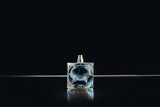 Close-up of an elegant black glass perfume bottle with delicate etched details reflecting soft light.