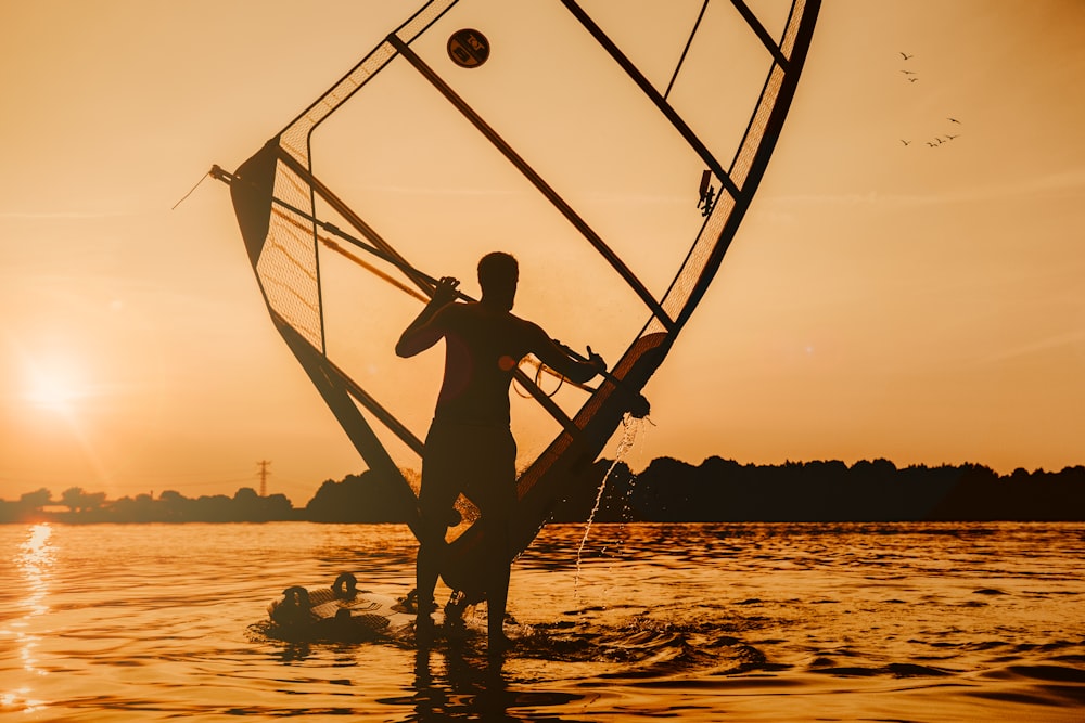 Man aan het windsurfen op zee tijdens de zonsondergang