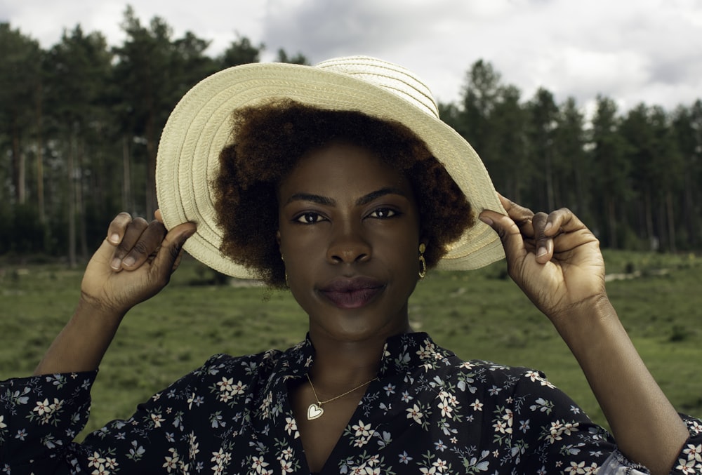 woman in white sun hat and black and white floral shirt