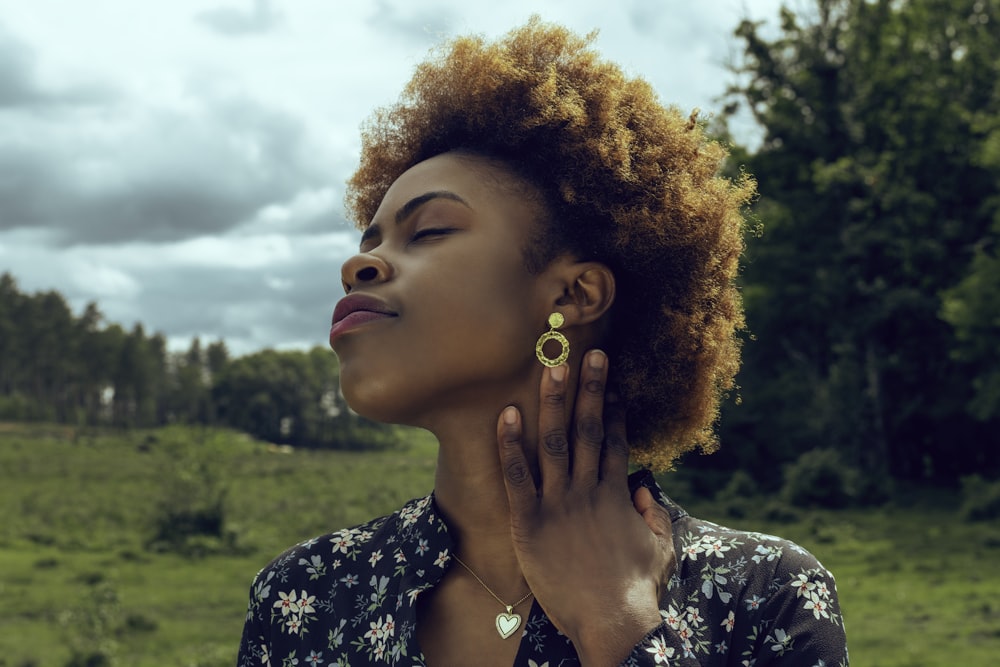 woman in black and white floral shirt with gold earrings