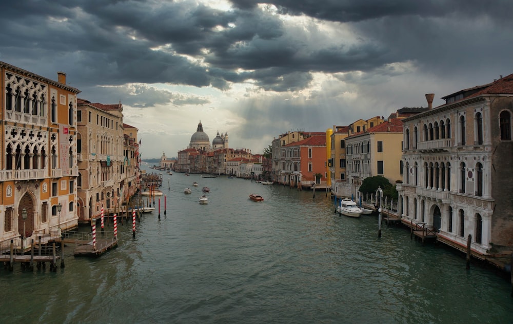 boat on water between buildings under cloudy sky during daytime