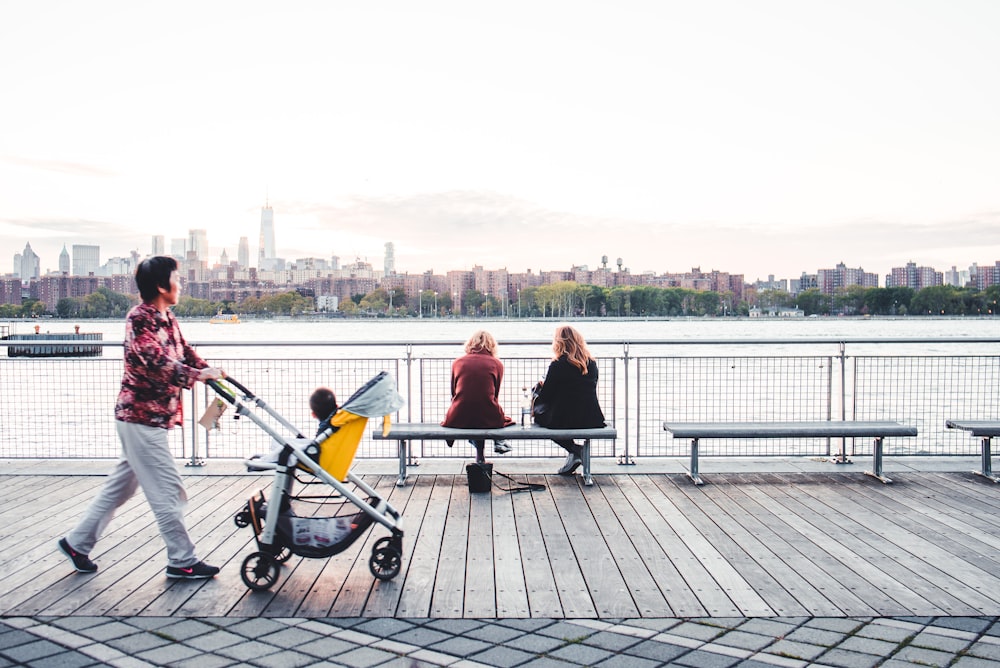 people sitting on black metal bench near body of water during daytime