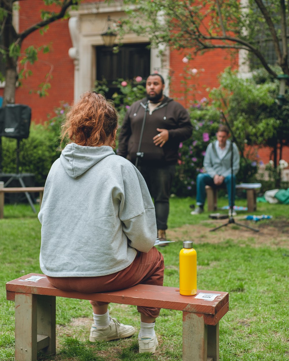 woman in gray hoodie sitting on brown wooden bench