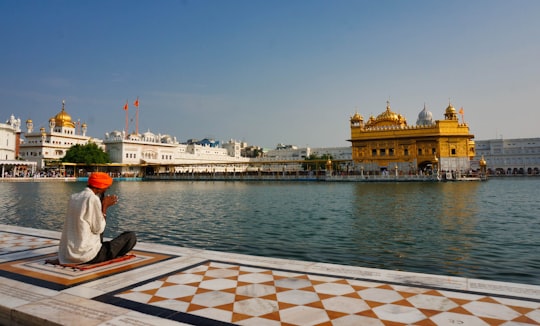 white and brown ship on sea near brown and white building during daytime in Harmandir Sahib India