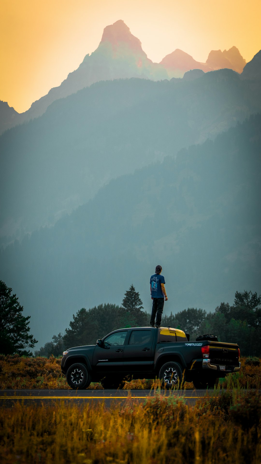 man in black jacket standing on yellow car during daytime