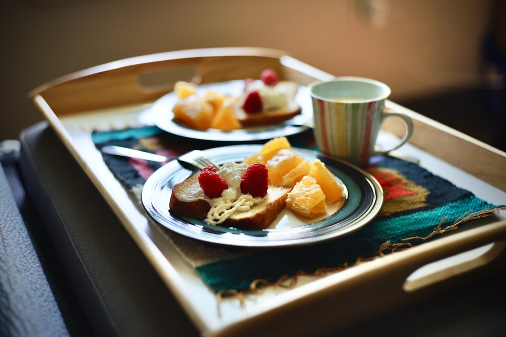 fruta en rodajas en plato de cerámica blanca junto a taza de cerámica blanca en mesa de madera marrón