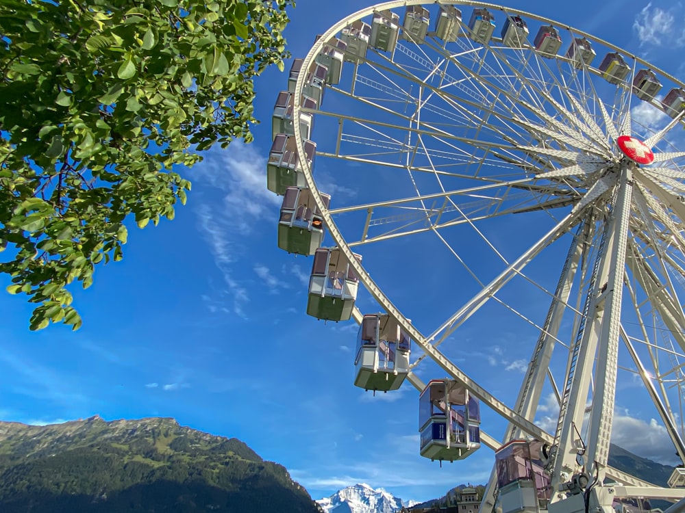 personas que viajan en la rueda de la fortuna blanca bajo el cielo azul durante el día