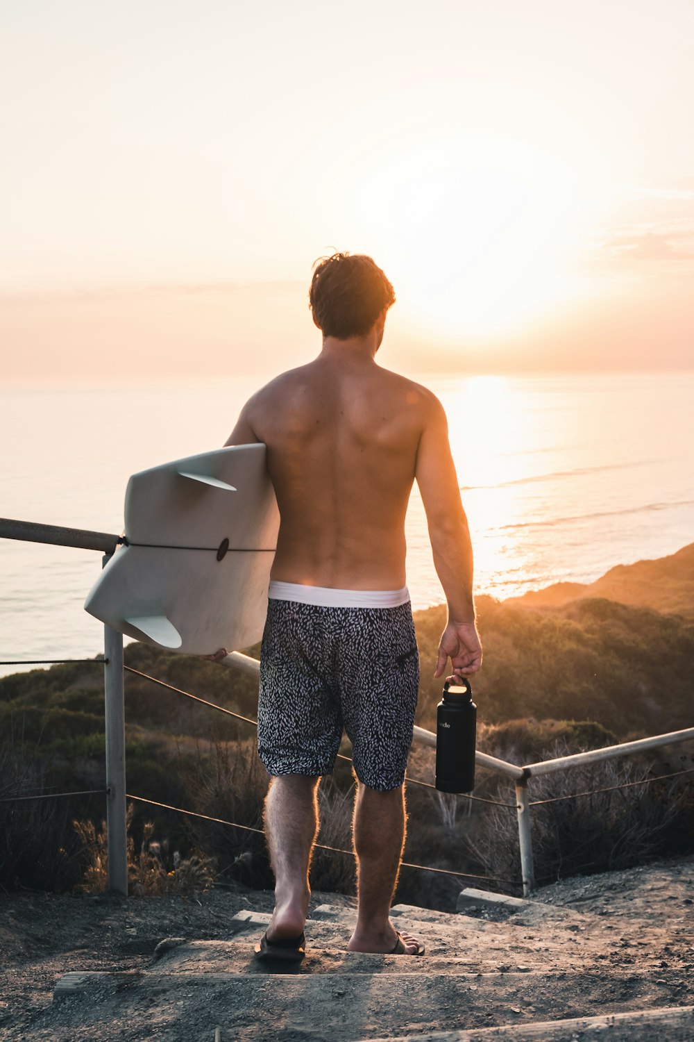 man in black and white shorts holding blue glass bottle