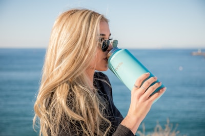 woman in black long sleeve shirt holding blue plastic bottle