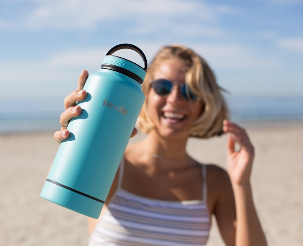 Frau in weißem Tanktop mit blauem und schwarzem Becher