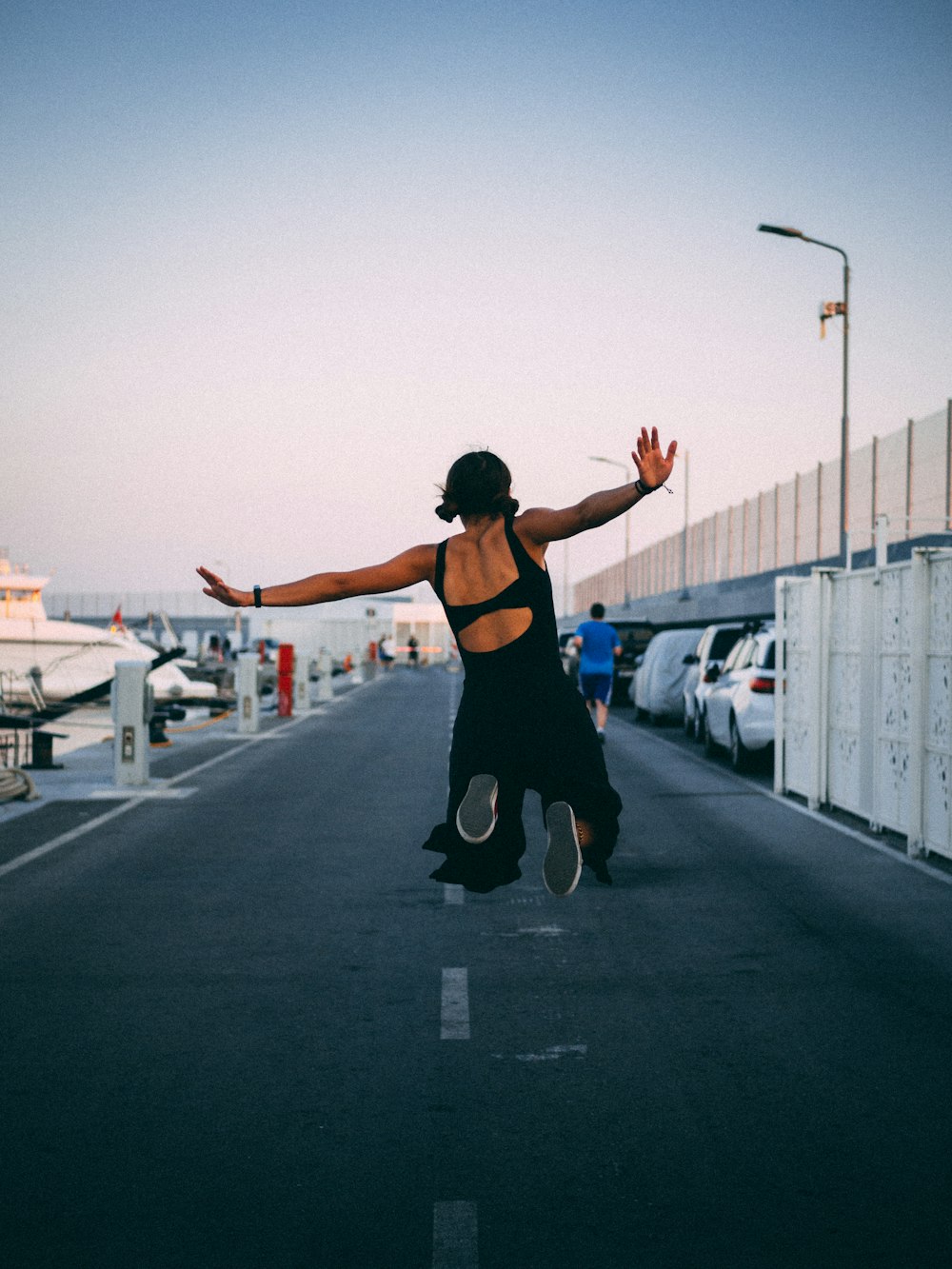 woman in black sports bra and black shorts doing yoga on gray asphalt road during daytime