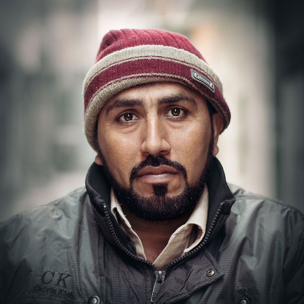 man in black leather jacket wearing red and white knit cap