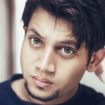 Close-up portrait of a young man with expressive eyes against a simple backdrop.