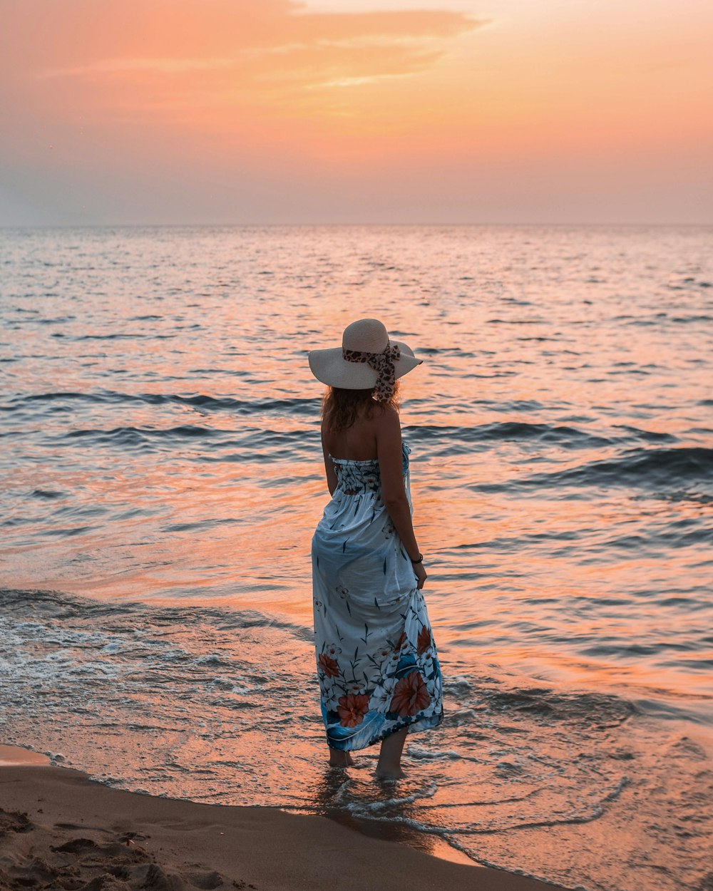 woman in blue and white floral dress standing on beach during daytime