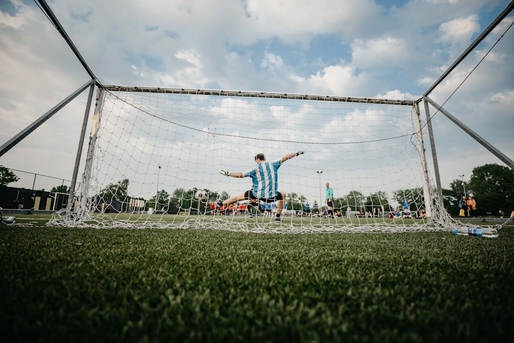 boy in blue shirt playing soccer during daytime