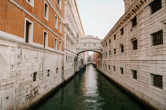 brown concrete building beside river during daytime in Bridge of Sighs Italy